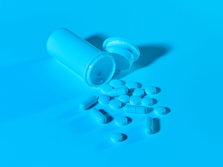A pillbox with pills spilling out under blue lighting