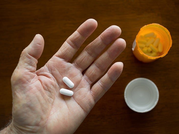 An open hand holding two white pills