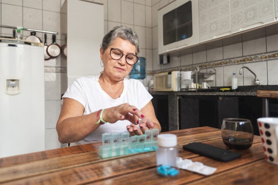 woman in her kitchen organizing pills and tablets