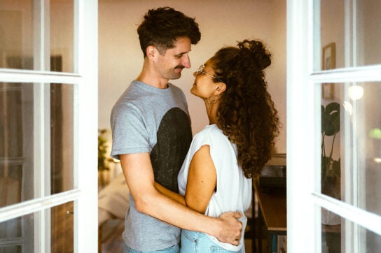 An Image of a couple with their hands around each other, staring at one another.