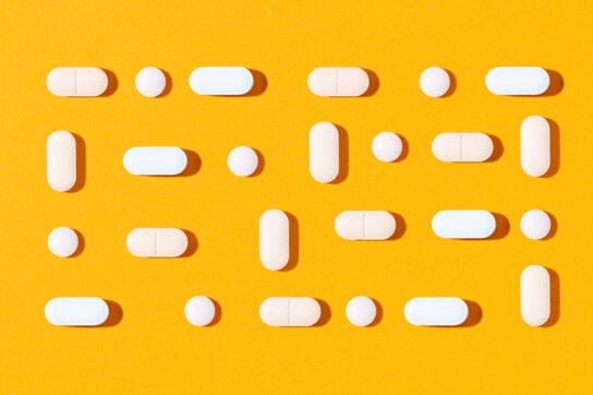 White rectangular pills and small white circular pills making a rectangle shape and evenly spaced to represent degenerative disc disease medication
