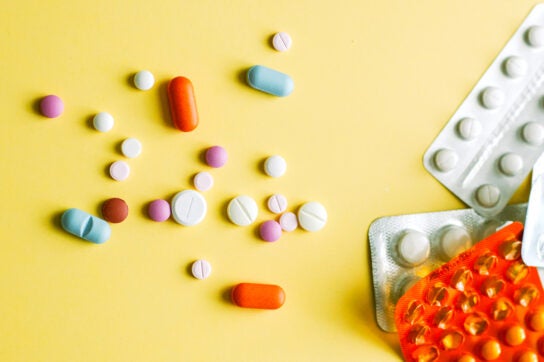 Various pills and tablets scattered on a yellow background