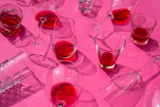 Glasses of red wine on a pink table.