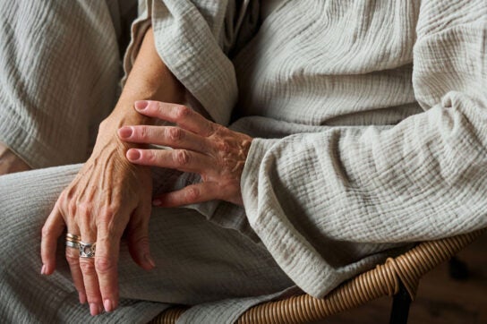 Close up of older adult female touching her wrist with her hand depicting psoriatic arthritis vs. rheumatoid arthritis